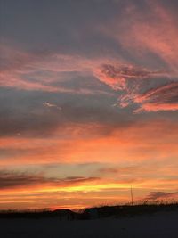 Scenic view of dramatic sky over silhouette landscape during sunset