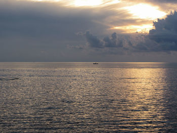 Warm sea sunset with little fishing boat on the water . giants cumulonimbus clouds in the sky