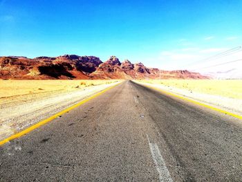 Road leading towards mountain against sky