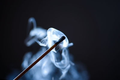 Close-up of incense stick emitting smoke