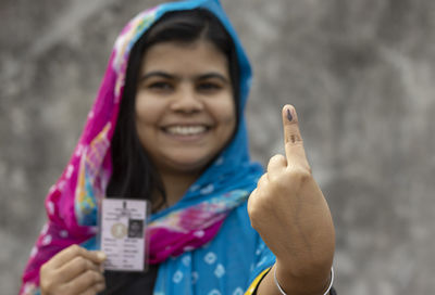 Selective focus on ink-marked finger of an indian village woman with smiling face and voter card