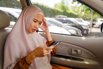 Portrait of young woman sitting in car