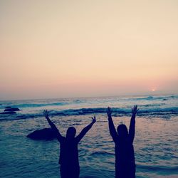 Silhouette people at beach against sky during sunset