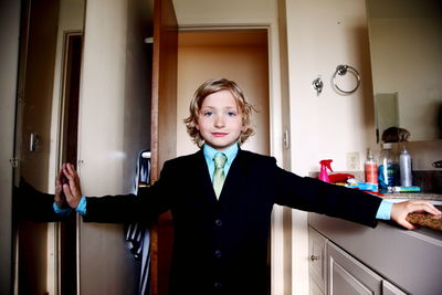 Close-up portrait of boy wearing suit standing against door at home