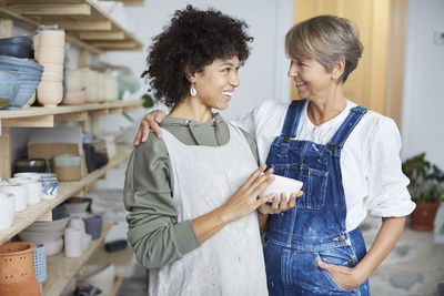 Smiling females with bowl in pottery class