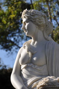 Low angle view of angel statue against trees