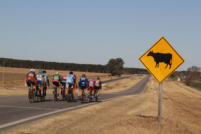 People riding bicycle on road against clear sky