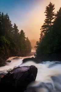 Scenic view of waterfall against sky during sunset