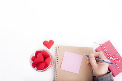 Close-up of hand holding book over white background