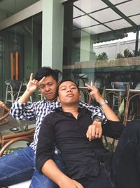 Full length portrait of happy young man sitting outdoors