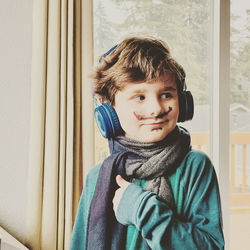 Portrait of boy looking through window at home