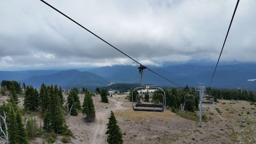 Ski lift over landscape against cloudy sky