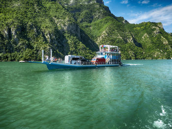 Boat sailing on sea against mountain