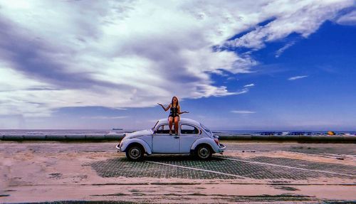 Car on road by sea against sky