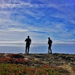 Silhouette men standing on beach against sky