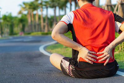 Rear view of man sitting on footpath