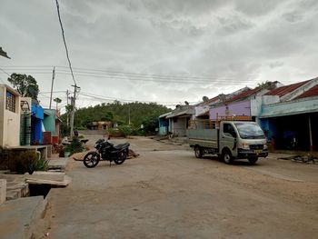 Cars on street by buildings against sky