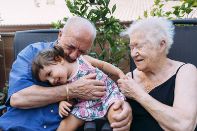 Grandparents and granddaughter having fun together on terrace