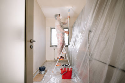 Man working with paint roller in kitchen at home