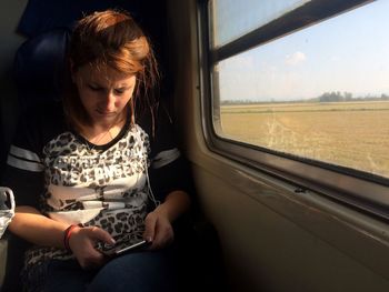Woman using phone while sitting in train
