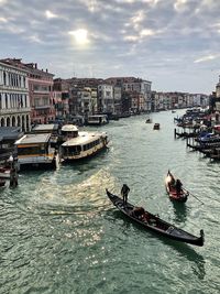 Boats in canal by city against sky