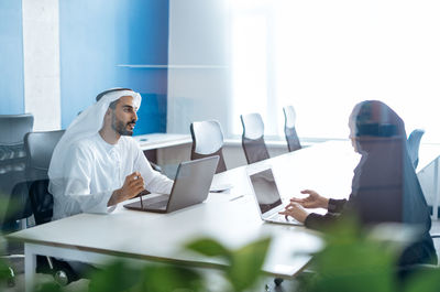 Rear view of woman using laptop at office