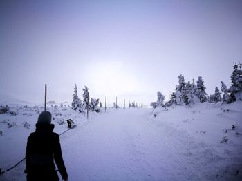 Rear view of man on snow field against clear sky