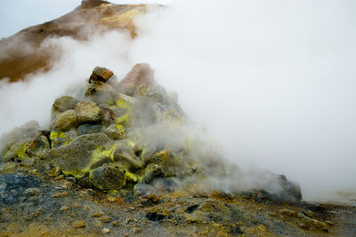Rocks pile amidst smoke in volcanic crater