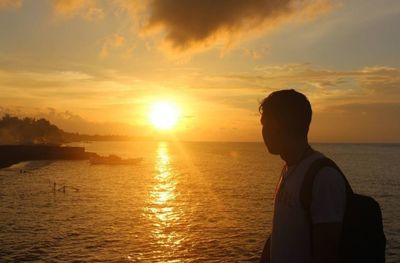 Man looking at sea against sky during sunset