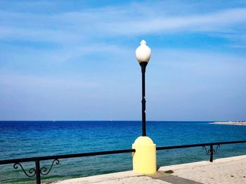 Street light by sea against sky