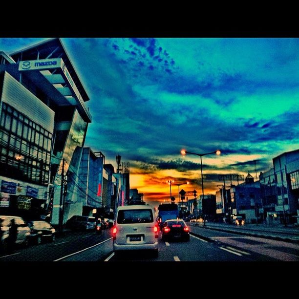 transportation, building exterior, car, architecture, built structure, land vehicle, sky, city, mode of transport, street, road, cloud - sky, city street, city life, traffic, cloudy, road marking, dusk, cloud, residential building