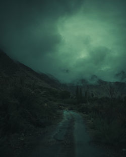 Dirt road amidst landscape against sky