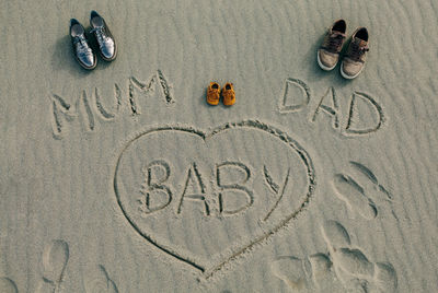 High angle view of shoes with text on sand at beach