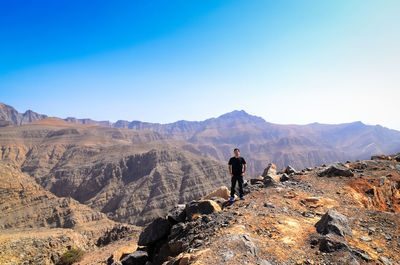Man standing on mountain peak against blue sky