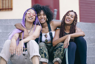 Portrait of smiling female friends sitting on steps