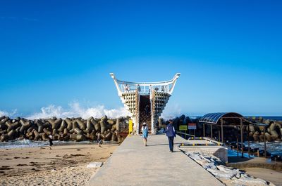 Rear view of people walking against blue sky