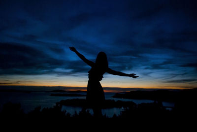 Silhouette woman with arms raised against sky during sunset