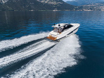 Boat sailing on sea against mountain