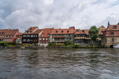 Buildings by river in town against sky