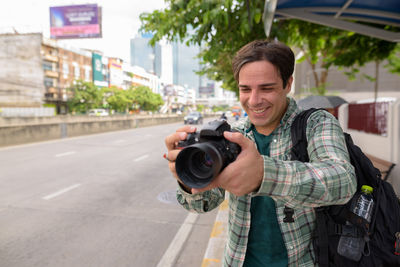 Portrait of man photographing near road