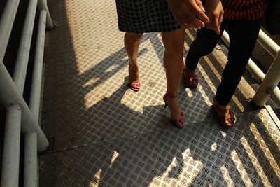 Low section of friends walking on footbridge