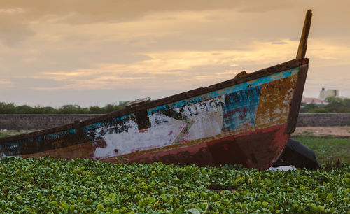 Abandoned boat against sky during sunset