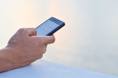 Midsection of man using mobile phone against sky