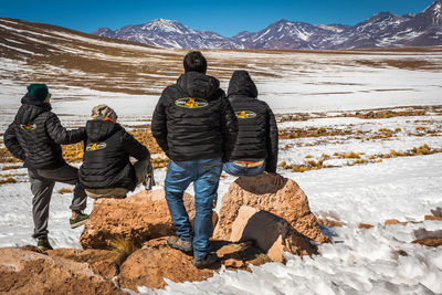Rear view of people on snowcapped mountains during winter