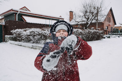 Close up outdoor winter portrait of boy playing snowballs. authentic, real, candid portrait of cute