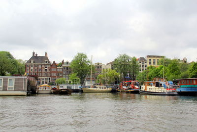 Buildings by river against sky in city