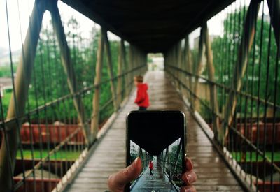 Person using mobile phone on footbridge