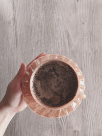 Directly above shot of hand holding coffee cup on table