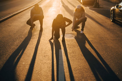 Full length of friends dancing on street in sunlight during sunset
