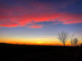 Silhouette bare tree on field against romantic sky at sunset